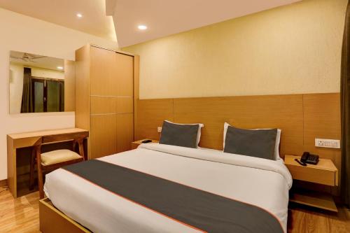 a bedroom with a large bed and a desk at Collection O Hotel Orange Regency in Dehradun