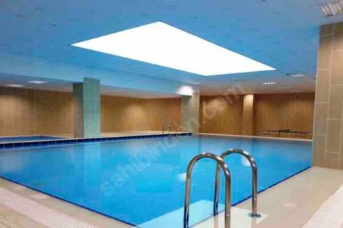 a large swimming pool with blue water in a building at Prestij beykent rezidance in Buyukcekmece