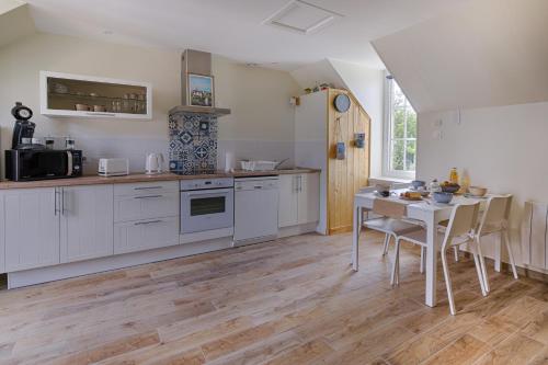 une cuisine avec des armoires blanches et une table avec des chaises dans l'établissement Duplex Le Louisels, à Bayeux
