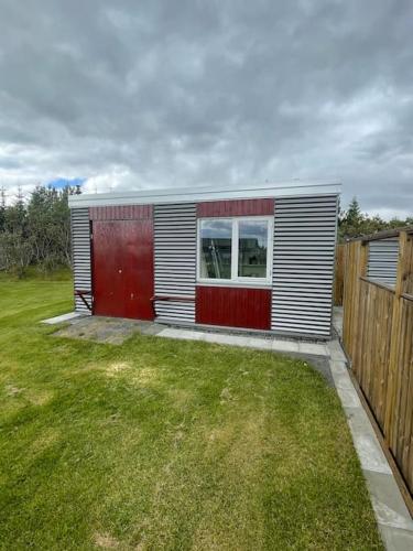 a small house in a yard next to a fence at Stunning house - amazing scenery in Hvolsvöllur