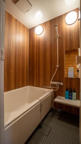a bathroom with a large tub and wooden walls at Wadano Gateway Suites & Apartments in Hakuba