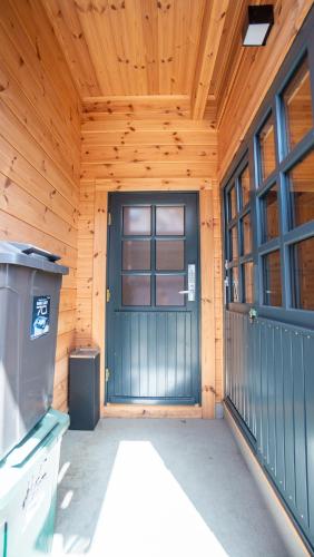 a front door of a wooden cabin with a trash can at Wadano Gateway Suites & Apartments in Hakuba