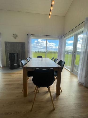 a dining room table with chairs and a large window at Stunning house - amazing scenery in Hvolsvöllur