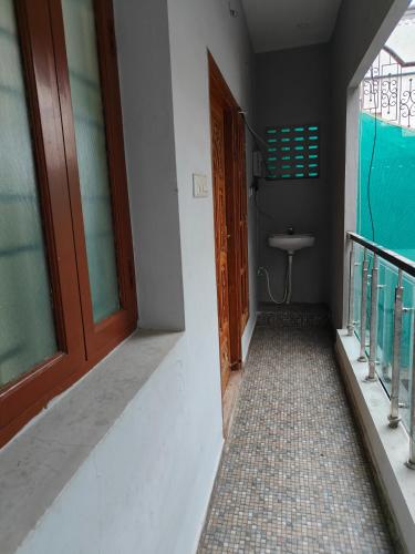 Fiona Homestay في تشيناي: ممر فيه باب ومغسلة في غرفة