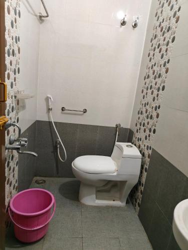 a bathroom with a toilet and a pink bucket at Fiona Homestay in Chennai