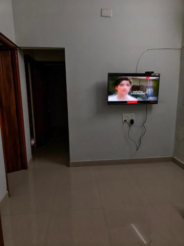 TV de pantalla plana colgada en una pared blanca en Fiona Homestay, en Chennai