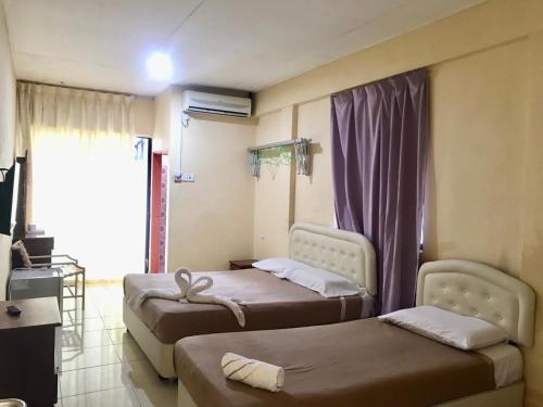 a hotel room with two beds and a tv at ANZ LANGKAWI INN in Pantai Cenang