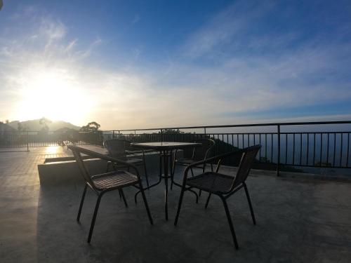 a table and chairs on a balcony with the sunset at leisure Mount View in Haputale