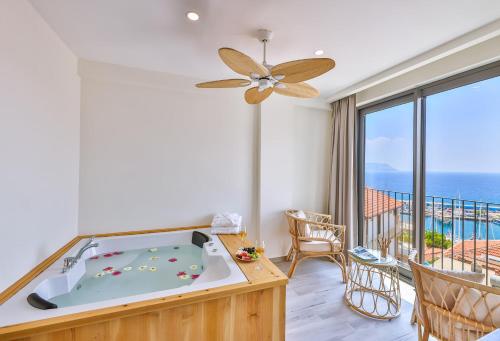 a room with a tub and a balcony with the ocean at Kas Athena Hotel in Kas