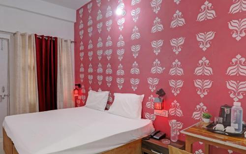 1 dormitorio con cama blanca y pared roja en Hotel Surya Inn, en Pura Raghunāth