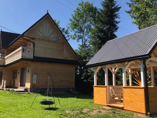 a house with a porch and a swing in the yard at Osada Witów - Domek we wsi in Witów