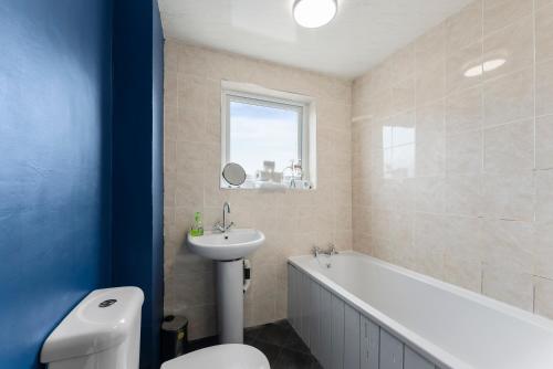 a bathroom with a tub and a sink and a toilet at Sleek and Stylish 3 Bed House - Great Location in Bolton