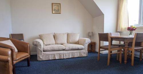a living room with a couch and a table and chairs at Poolewe Hotel in Poolewe