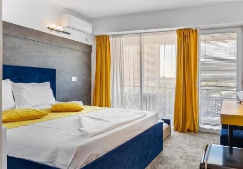 1 dormitorio con 1 cama grande y cortinas amarillas en Hotel Aqua Park en Eforie Nord