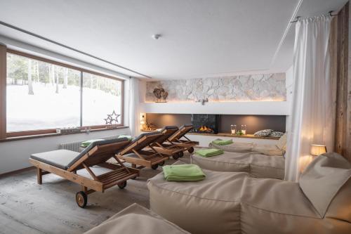 a living room with chairs and a fire place at Hotel Ciasa Ai Pini in San Cassiano
