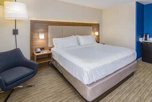 Holiday Inn Express Southington, an IHG Hotel في ساوثينجتون: سرير وكرسي في غرفة الفندق