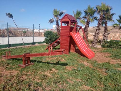 een speeltuin met een rode glijbaan in het gras bij Disney land villa in Gourizim