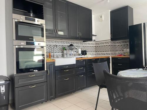 La cuisine est équipée de placards noirs et d'un four avec plaques de cuisson. dans l'établissement chez Catherine tres beau logement tout équipé et proche des transports, à Marseille