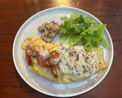 a plate of food with shrimp and greens on a table at Griya Shanti Suites in Sanur
