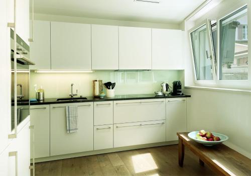 a kitchen with white cabinets and a bowl of fruit on a table at Stay at Night - Moonlight in Zürich