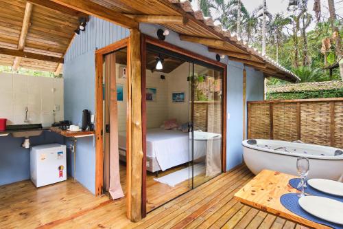 a room with a bath tub and a bedroom at Refúgio na Mata Atlântica com Ofurô Aquecido in Ubatuba