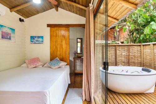 a bathroom with a tub and a bed in a room at Refúgio na Mata Atlântica com Ofurô Aquecido in Ubatuba