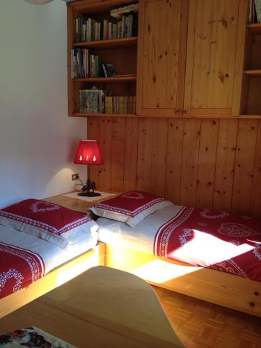 two beds in a room with a lamp and bookshelves at Villa Montana in Moena