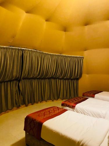 two beds in a room with yellow walls at Syndebad desert camp in Wadi Rum