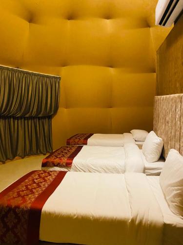 two beds in a room with yellow walls at Syndebad desert camp in Wadi Rum