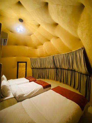 a bedroom with two beds and a stone wall at Syndebad desert camp in Wadi Rum