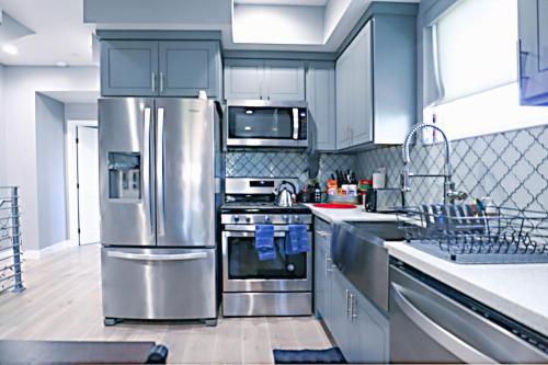 a kitchen with stainless steel appliances and blue cabinets at Lucky Charm 4 Bedroom Mid-City Apartment in Los Angeles