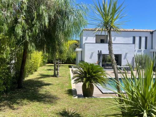 a house with a swimming pool and palm trees at Le Minamo Studio in Six-Fours-les-Plages