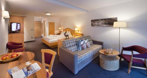 a living room with a couch and a bed in a room at Hotel Alpenroyal in Castelrotto