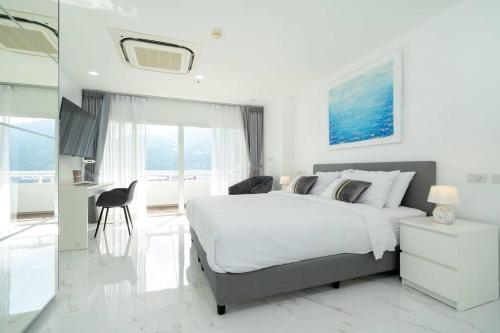 a white bedroom with a large bed and a bathroom at Patong Tower Brand New 1-Bedroom , Near Beach in Patong Beach