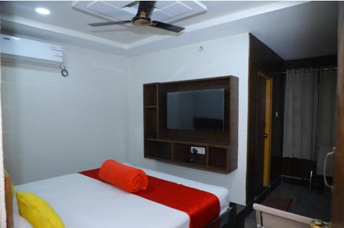 a bedroom with two beds and a tv on the wall at Hotel New Maruthi Inn, LB Nagar in Hyderabad