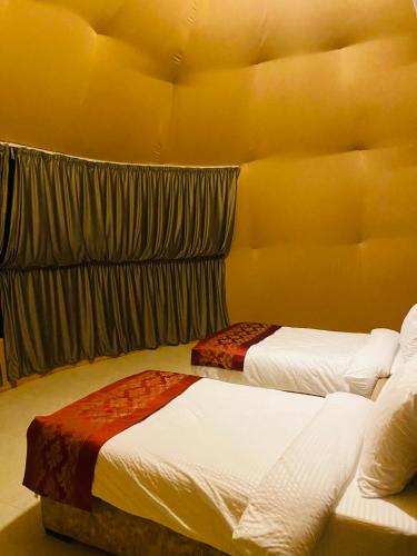 two beds in a room with yellow walls at Syndebad desert camp in Wadi Rum