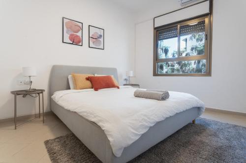 une chambre blanche avec un grand lit avec une fenêtre dans l'établissement Eliezer Ben Yehuda Residence WITH SHELTER, à Tel Aviv