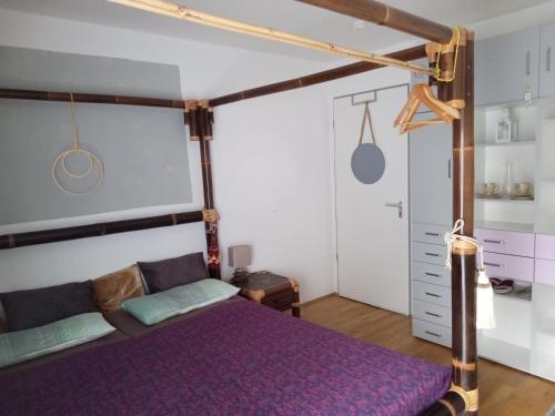 ein Schlafzimmer mit einem Bett mit einer lila Tagesdecke in der Unterkunft Ferienwohnung in München