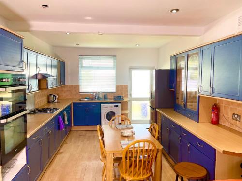 South NorwoodにあるE-Sky Homesのキッチン(青いキャビネット、テーブル、椅子付)