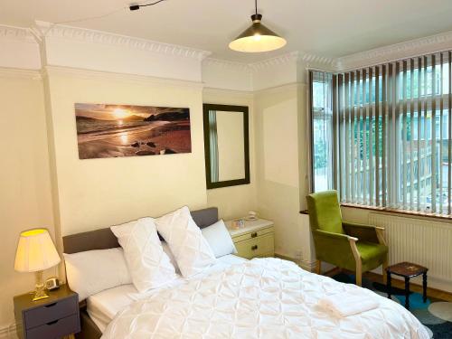 a bedroom with a white bed and a green chair at E-Sky Homes in South Norwood