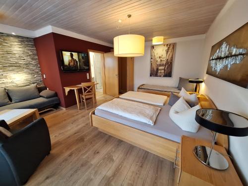 a living room with a bed and a couch at Hotel Garni Pension Zur Krone in Hilpoltstein