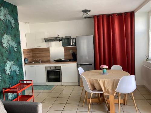 eine Küche mit einem Tisch und einem roten Vorhang in der Unterkunft Appartement T2 cosy in La Rochelle