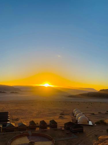 a sunset over a desert with a group of tents at Syndebad desert camp in Wadi Rum