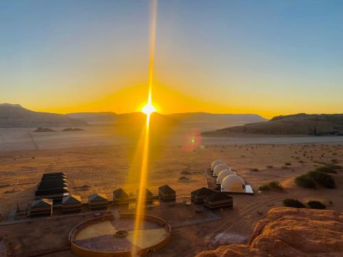 a sunset in the desert with chairs and a fountain at Syndebad desert camp in Wadi Rum