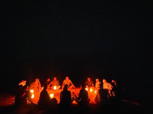 a group of people sitting around a bonfire at night at Syndebad desert camp in Wadi Rum