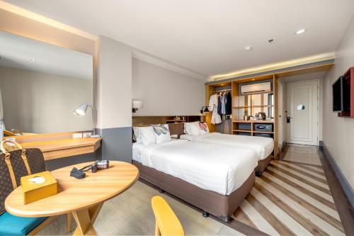 Vince Hotel Pratunam في بانكوك: غرفة في الفندق بسرير ومكتب وطاولة