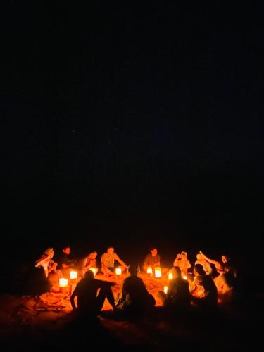 a group of people sitting around a fire at night at Syndebad desert camp in Wadi Rum