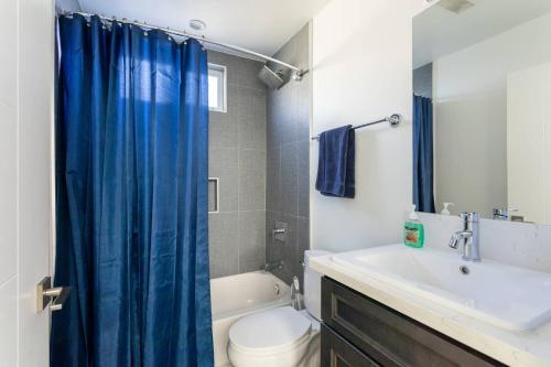 a bathroom with a toilet and a blue shower curtain at Cheerful 4BR home with parking in East Hollywood in Los Angeles