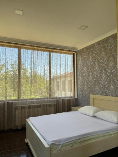 a bedroom with a large bed and large windows at Guest House MIRA in Martvili
