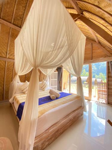 a bedroom with a bed with a mosquito net at Batur cottage in Kubupenlokan